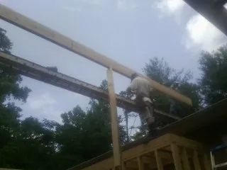 Carpenter setting a ridge beam over a new addition frame — Ice Dam Removal by Roofing Brothers in Wayland