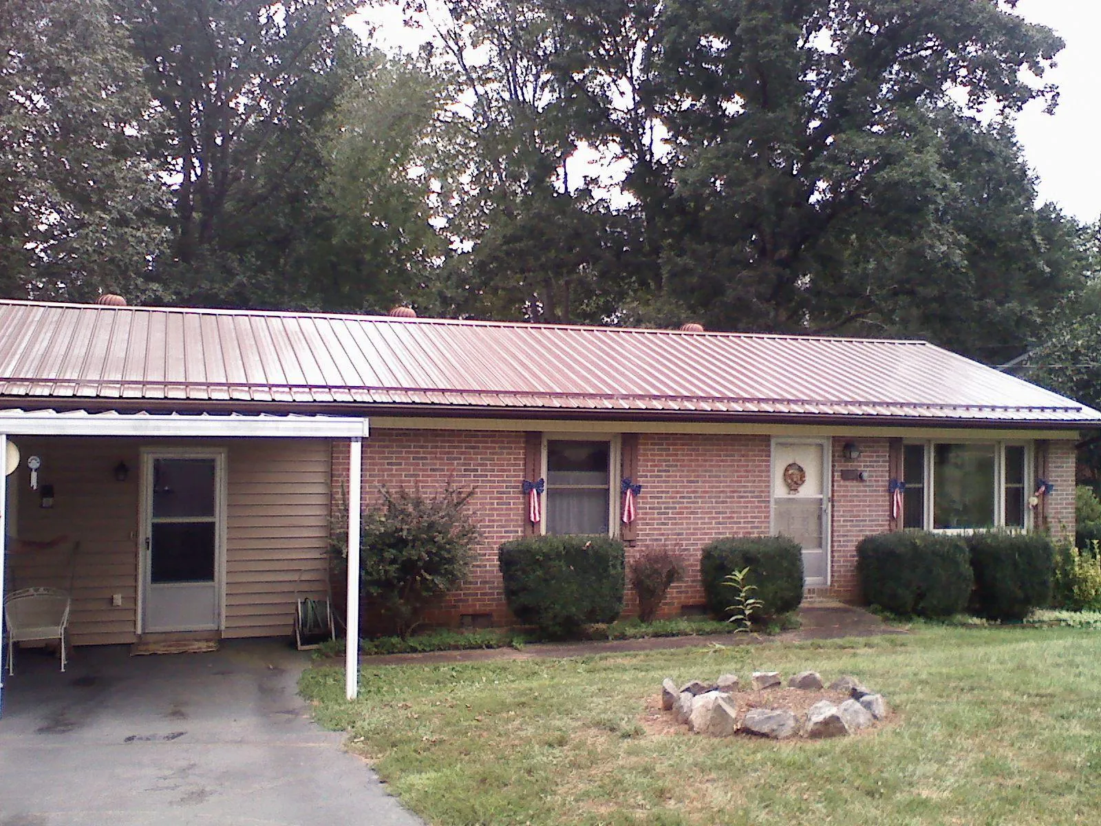 Bronze metal roof and carport on a brick ranch home — Roof Repair work by our crew in Wayland